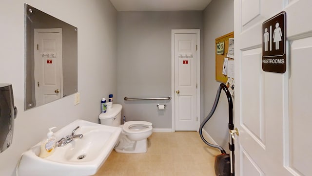 bathroom with a sink, baseboards, toilet, and electric panel