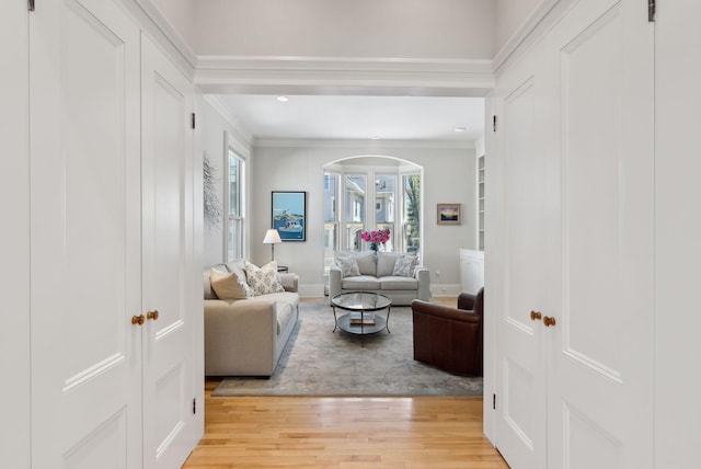 living room with recessed lighting, baseboards, ornamental molding, and light wood-style flooring