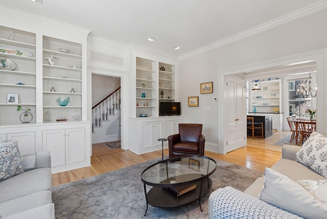 living area featuring stairway, ornamental molding, built in features, and light wood finished floors