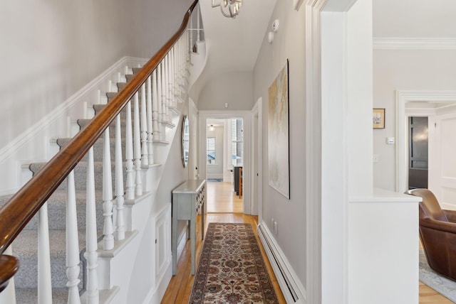 corridor featuring light wood-style floors, a baseboard radiator, stairway, and ornamental molding