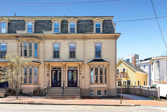 second empire-style home featuring mansard roof, fence, and entry steps