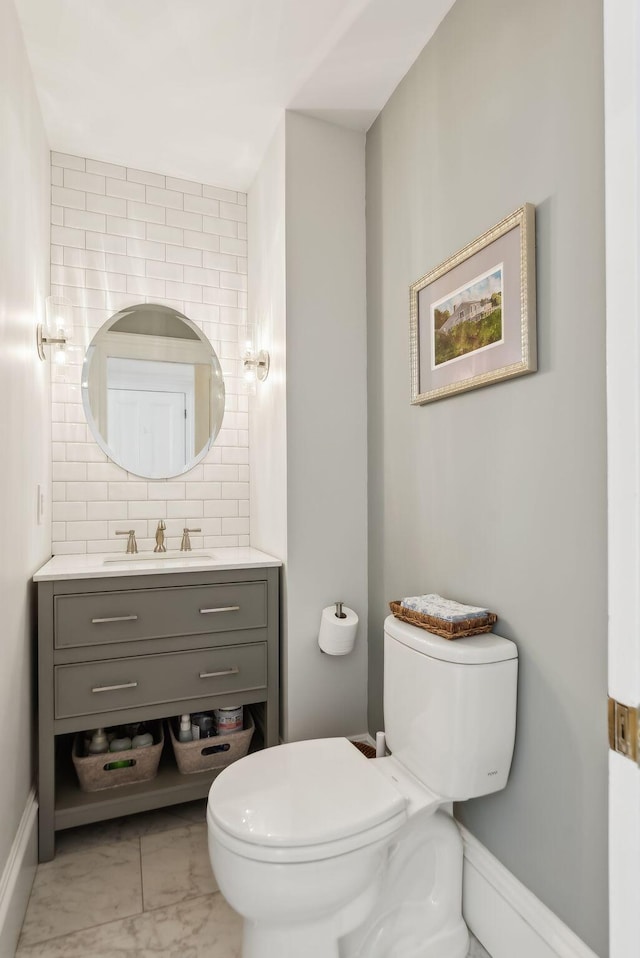 bathroom featuring toilet, baseboards, marble finish floor, and vanity