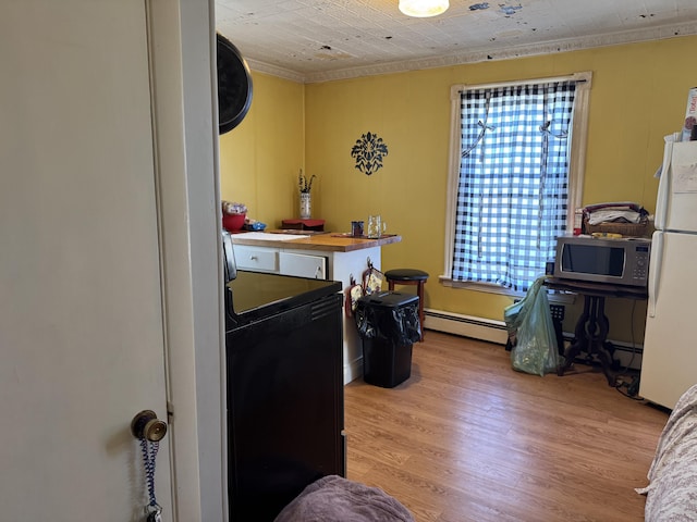 6 Spring St, Waterville, ME 04901 - kitchen with stainless steel microwave, a baseboard radiator, freestanding refrigerator, washer / clothes dryer, and light wood-type flooring