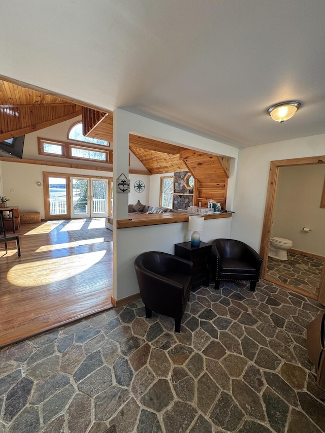 living area featuring lofted ceiling and stone flooring