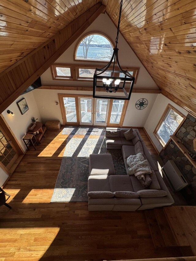 living area with wooden ceiling, wood finished floors, high vaulted ceiling, and a healthy amount of sunlight