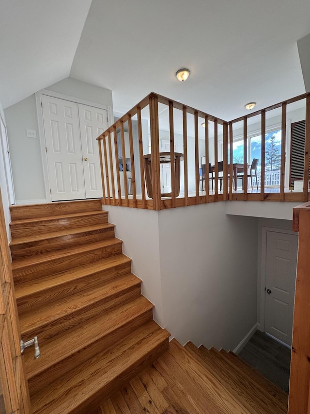 stairs featuring vaulted ceiling and wood finished floors