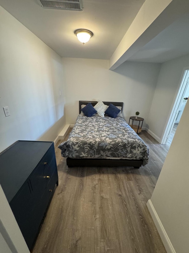 bedroom with visible vents, baseboards, and wood finished floors