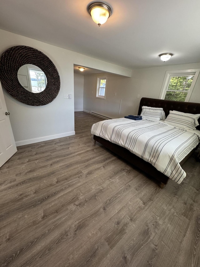 bedroom featuring a baseboard radiator, baseboards, and wood finished floors