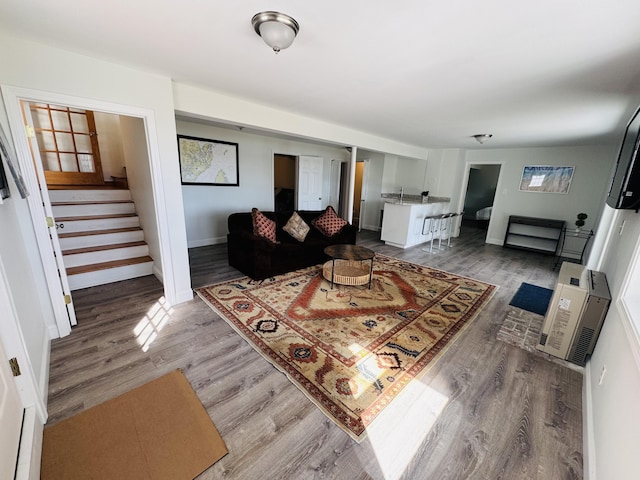 living area featuring stairs, heating unit, and light wood-style floors