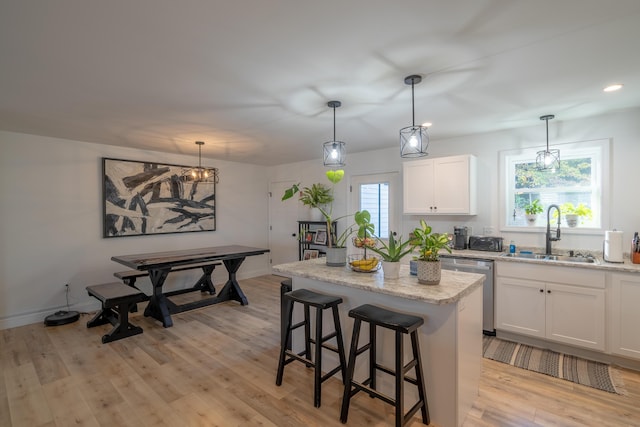 39 Firefly Ln, Bangor, ME 04401 - kitchen featuring stainless steel dishwasher, a kitchen island, light wood-type flooring, white cabinets, and a kitchen breakfast bar