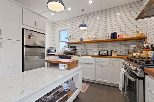 kitchen with open shelves, decorative backsplash, butcher block countertops, a sink, and appliances with stainless steel finishes