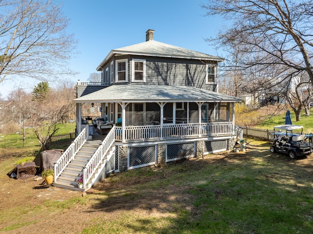 view of front of house with a front lawn, fence, roof with shingles, a chimney, and a sunroom