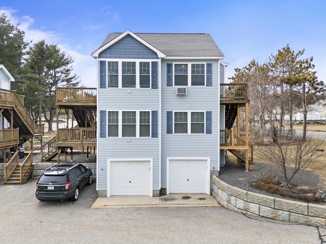 view of front of home with a deck, driveway, stairs, and a garage
