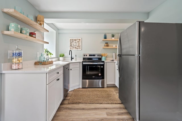 kitchen with white cabinetry, open shelves, light wood-style floors, appliances with stainless steel finishes, and a sink