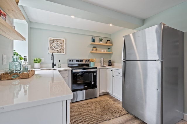 kitchen featuring light wood-style flooring, open shelves, white cabinets, a sink, and stainless steel appliances