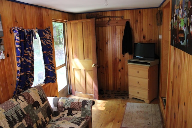 bedroom with light wood-style flooring and wood walls
