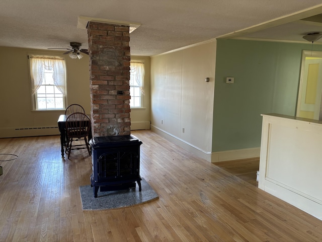 20 Water St, Winterport, ME 04496 - living room featuring a wood stove, wood-type flooring, baseboard heating, a baseboard heating unit, and ornamental molding