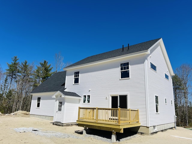 rear view of property featuring a wooden deck and a shingled roof