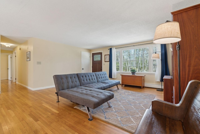 living area featuring a baseboard heating unit, light wood-type flooring, and baseboards
