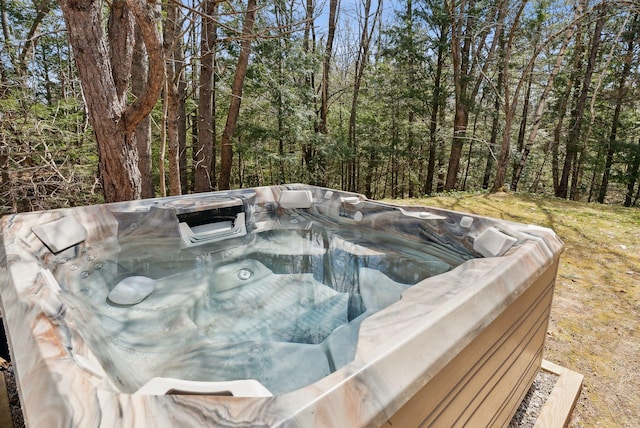 view of pool featuring a view of trees and a hot tub
