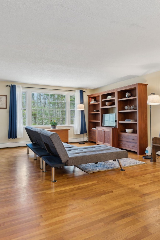 interior space featuring baseboard heating, a textured ceiling, and light wood-type flooring