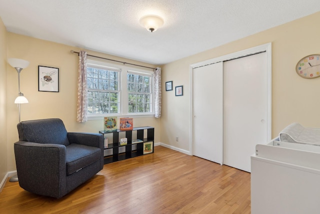 sitting room with baseboards and light wood-style flooring