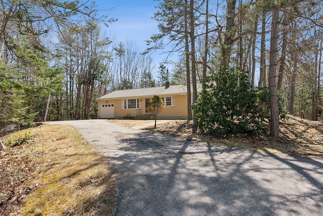 view of front of home with a chimney, aphalt driveway, and a garage