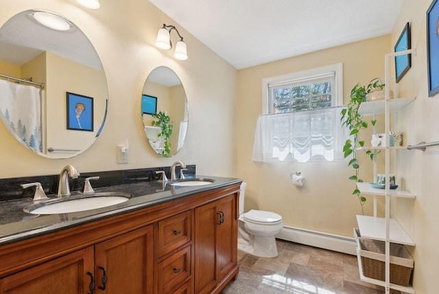 full bath with double vanity, toilet, baseboard heating, and a sink