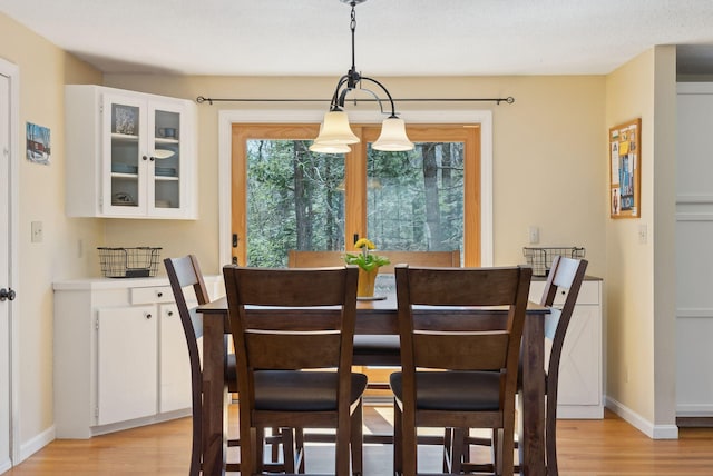 dining space with light wood finished floors and baseboards