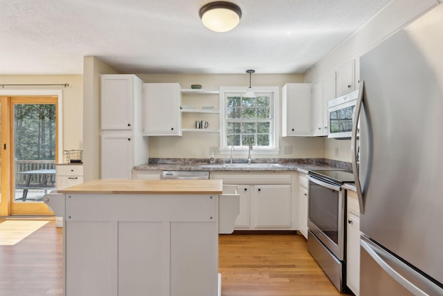 kitchen featuring light wood finished floors, white cabinets, a sink, and appliances with stainless steel finishes
