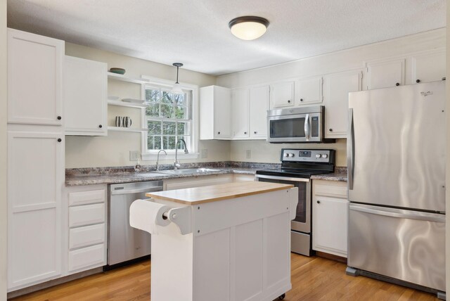 kitchen featuring a sink, light wood finished floors, white cabinets, appliances with stainless steel finishes, and a kitchen island