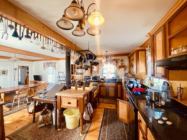 kitchen featuring brown cabinets, black appliances, a sink, and an inviting chandelier