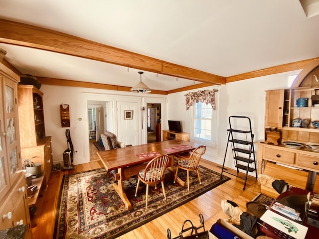 dining room featuring baseboards, beam ceiling, and hardwood / wood-style flooring