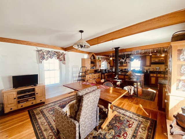 dining area with a wealth of natural light, beamed ceiling, wood finished floors, and ornate columns