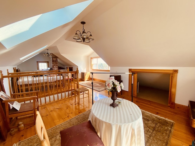 sitting room featuring vaulted ceiling with skylight, an upstairs landing, and hardwood / wood-style floors