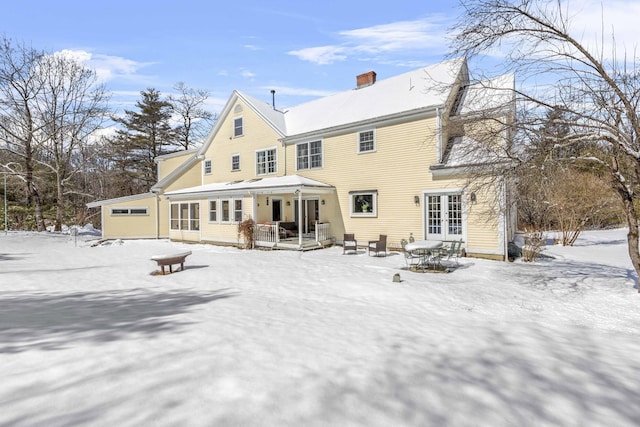 snow covered property featuring french doors and a chimney