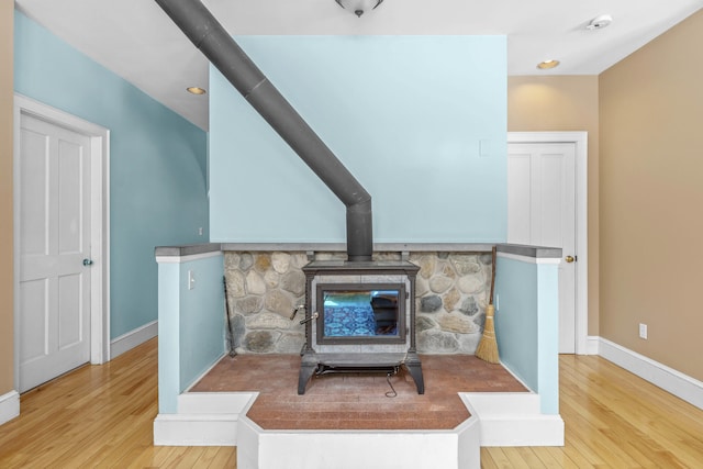 interior details with baseboards, wood finished floors, and a wood stove