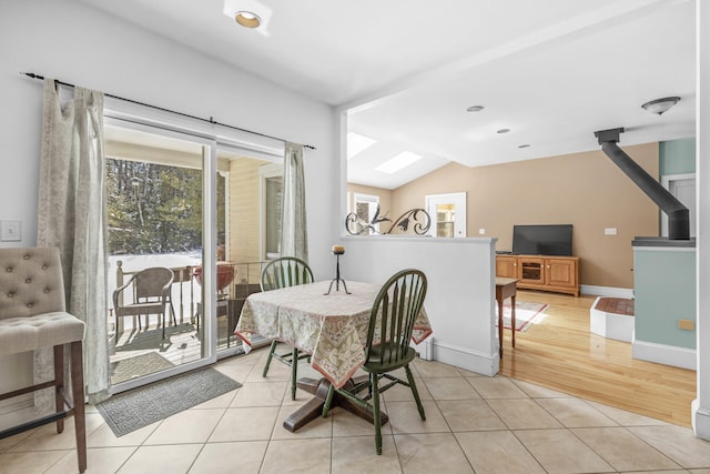 dining space with baseboards, light tile patterned floors, and vaulted ceiling