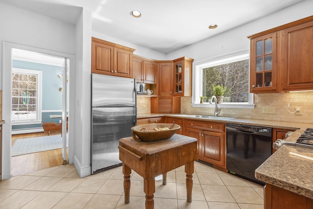kitchen with a sink, stainless steel refrigerator, dishwasher, and brown cabinets