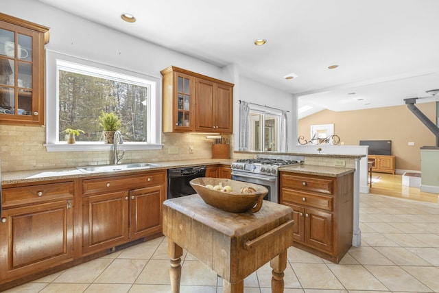 kitchen featuring a peninsula, high end stainless steel range, a sink, and tasteful backsplash
