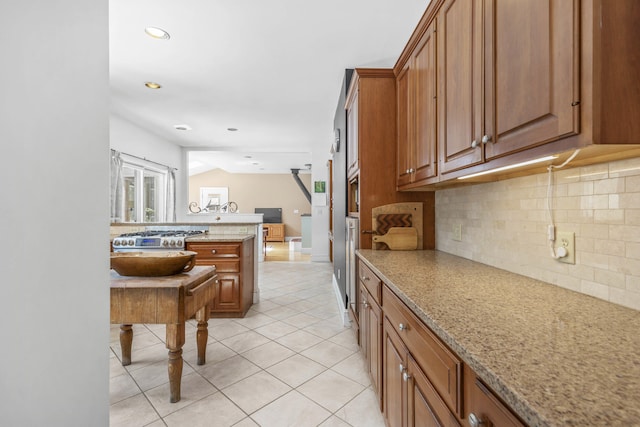 kitchen featuring brown cabinetry, tasteful backsplash, light stone countertops, light tile patterned floors, and recessed lighting