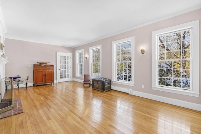 living room with light wood-style floors, ornamental molding, and baseboards