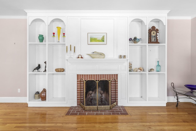 living area with crown molding, baseboards, a brick fireplace, and wood finished floors