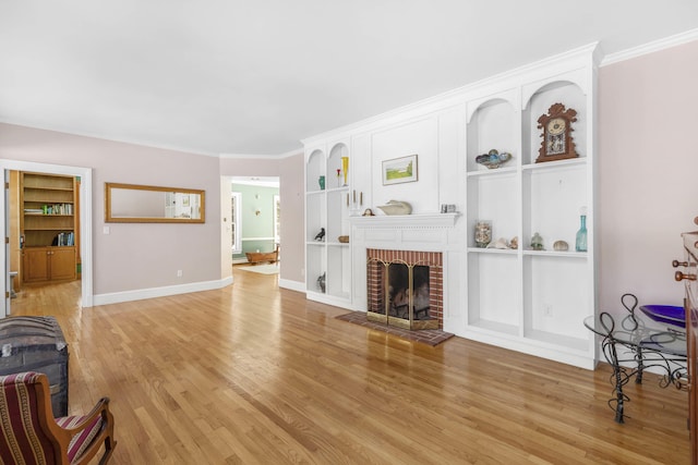 living room with built in features, baseboards, ornamental molding, and light wood-style flooring