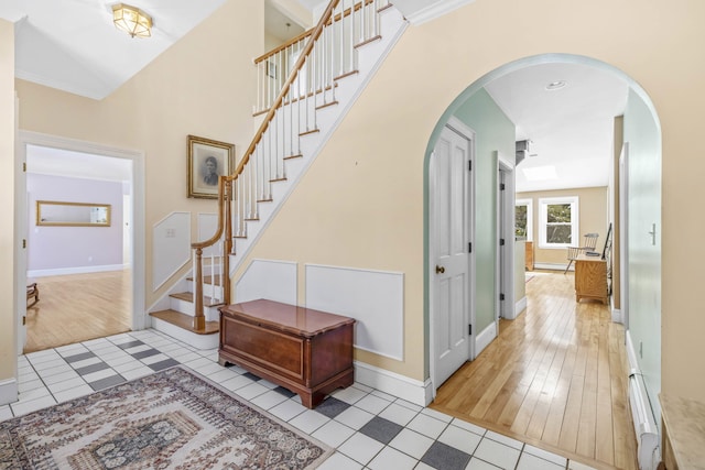 foyer entrance with baseboards, arched walkways, stairs, and light tile patterned floors