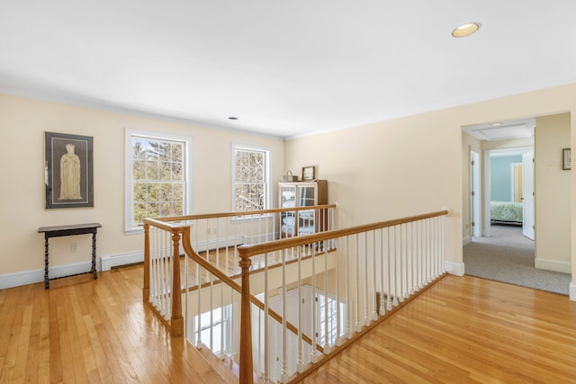 corridor featuring baseboards, recessed lighting, wood-type flooring, and an upstairs landing