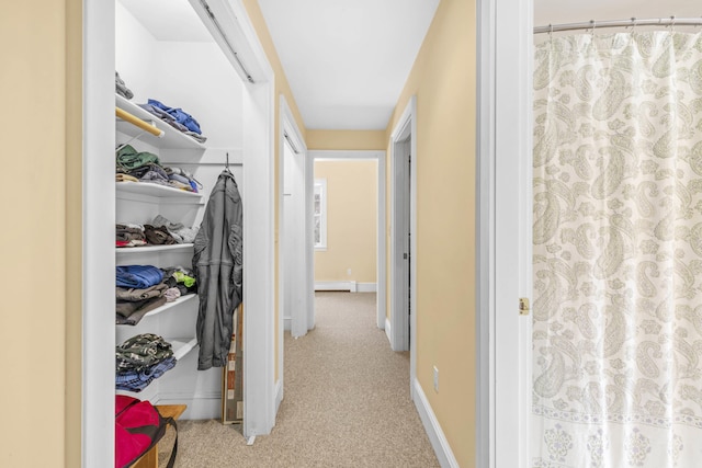 hallway featuring baseboards, a baseboard radiator, and carpet flooring