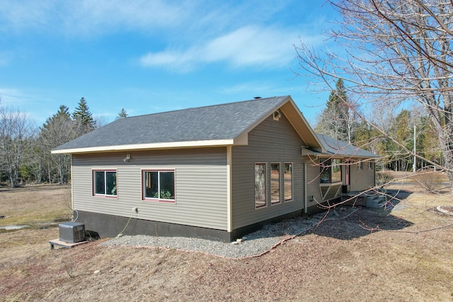 view of property exterior with central AC and roof with shingles