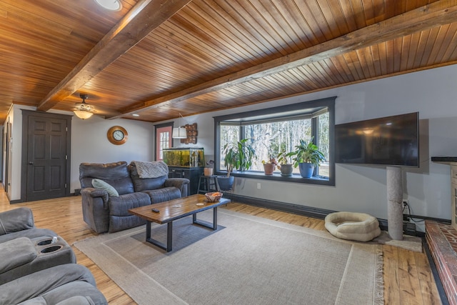 living area featuring baseboards, ceiling fan, wood finished floors, beam ceiling, and wooden ceiling