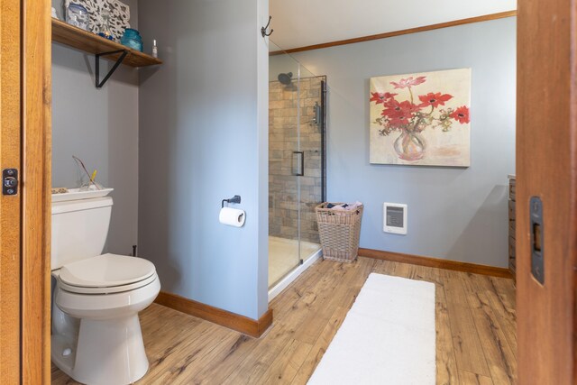 bathroom with wood finished floors, toilet, baseboards, and a shower stall